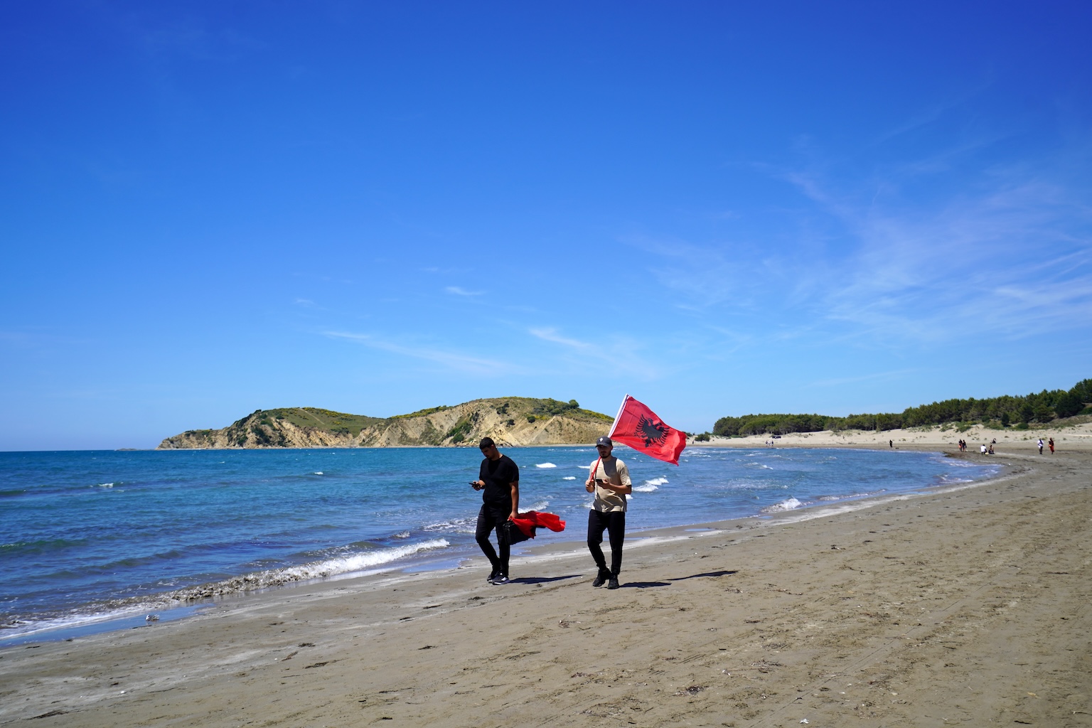 Demonstranten dragen een Albanese vlag langs het strand in de Vjosa-Narta-delta na een bijeenkomst op 6 juni. Afbeelding door Stefan Lovgren voor Mongabay.