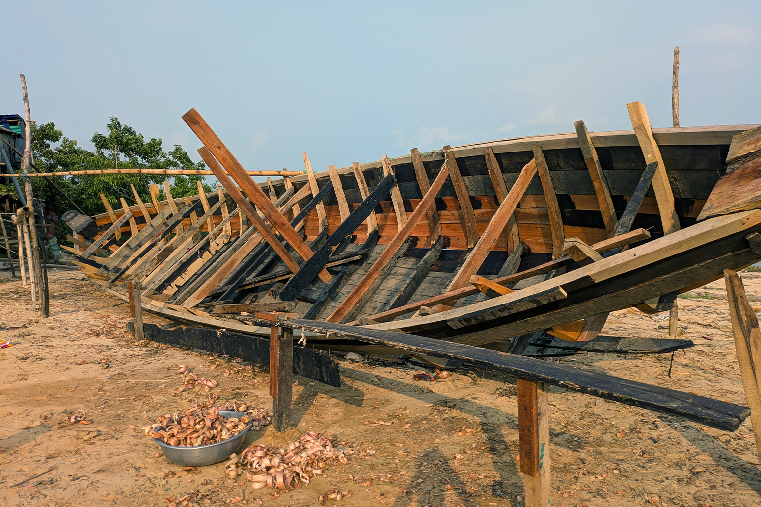 Een houten vissersboot wordt gerepareerd in Rangamati tijdens het jaarlijkse visverbod in het Kaptai-meer. Afbeelding door Sifayet Ullah.