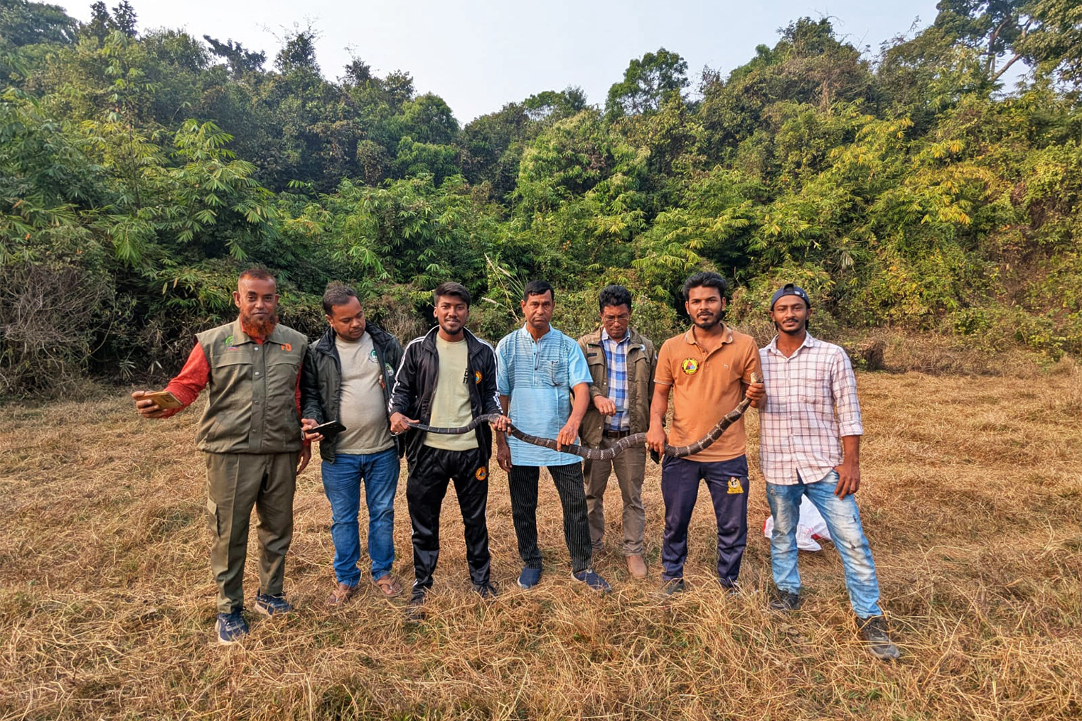 Ambtenaren van het Forest Department samen met lokale vrijwilligers na het redden van een grote slang. Afbeelding door Siddiqur Rahman Rabbi.