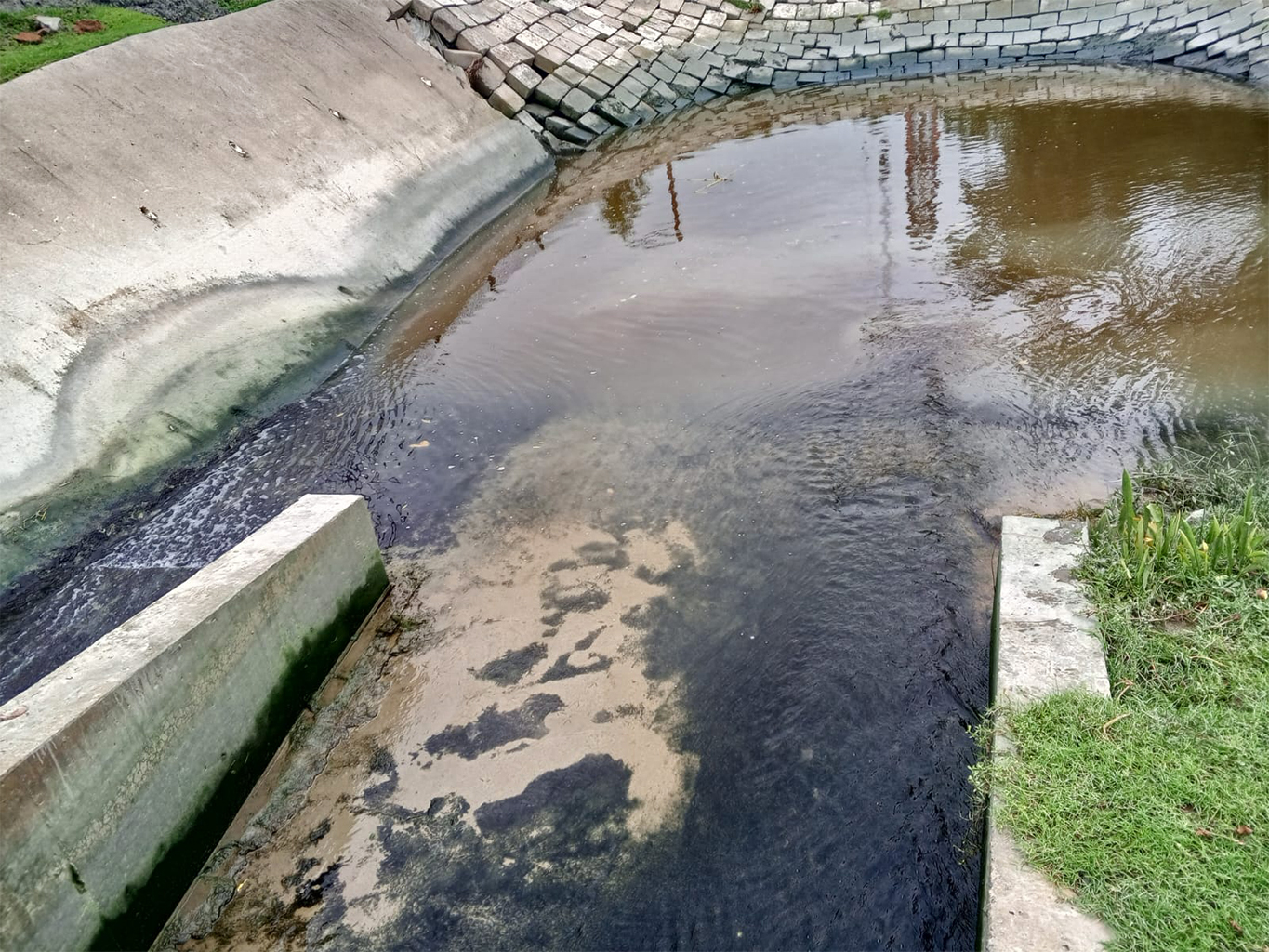 Zwart vervuild waterafvoer nabij de Payra-poort.