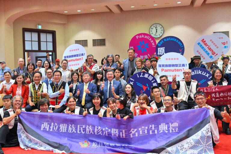 Uma Talavan, haar vader Cheng-hiong Talavan, haar echtgenoot Edgar Macapili, hun dochter Lici Talavan en andere leden van de inheemse gemeenschap van Siraya houden borden en spandoeken in de Chinese en Siraya-talen vast terwijl ze poseren met de Taiwanese premier Cho Jung-tai en andere regeringsfunctionarissen in Taipei op 30 juli 2026.