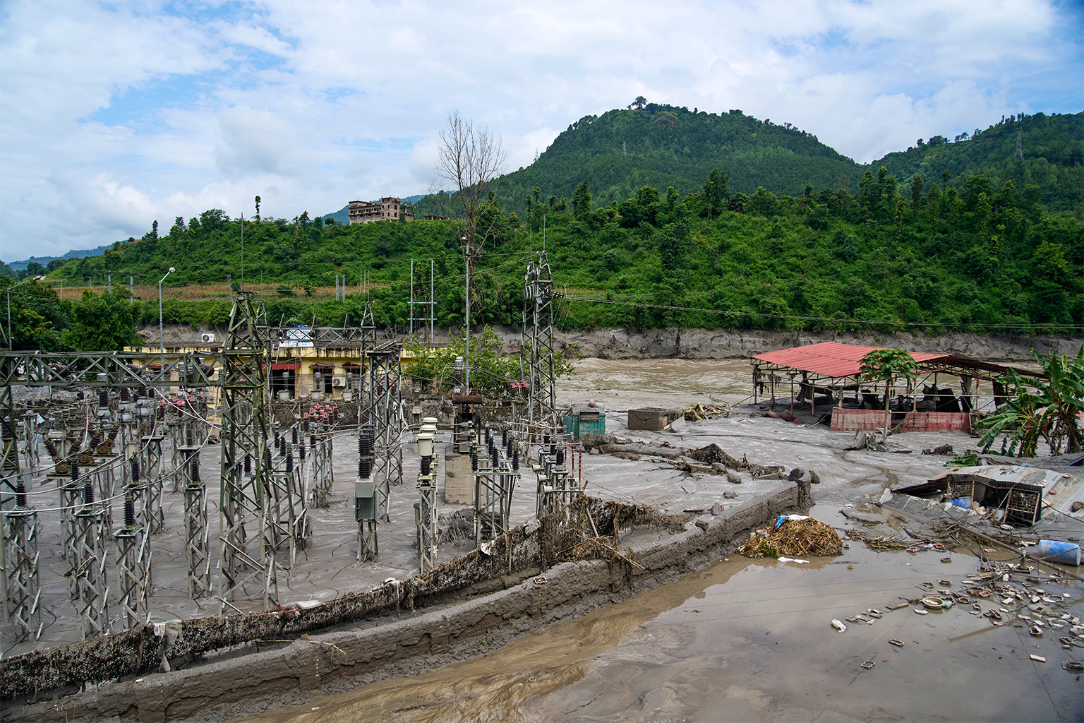 Een elektrische uitrusting van een elektriciteitscentrale is gedeeltelijk begraven in sneeuwbrij die door de Trishuli-rivier is aangevoerd tijdens plotselinge overstromingen, in het district Dhading, 30 augustus 2026.