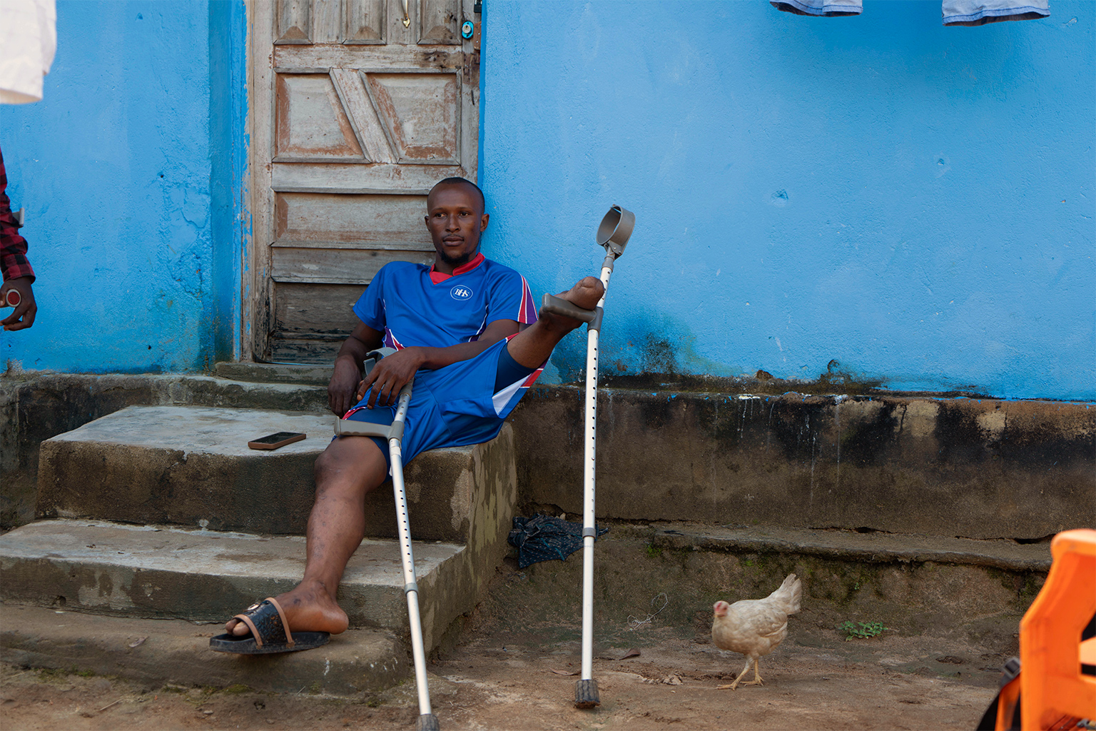 Alimany Kani zit buiten zijn huis in Waterloo, Sierra Leone. 