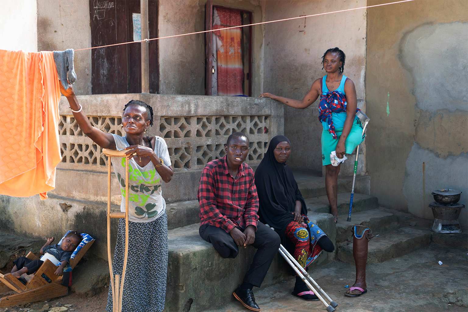 Geamputeerden zitten voor hun woningen gebouwd door buitenlandse NGO's in Freetown, Sierra Leone.