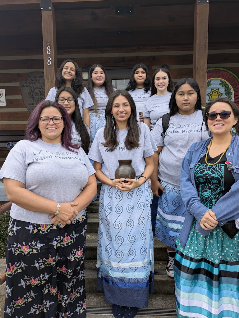 Junior NAIWA Daughters staan ​​met de Longperson voor de Eastern Band of Cherokee Council. Achterste rij (Janée Smith, Zailiana Blythe, Laila Crowe-Taylor, Misha Slee) Tweede rij (Kyndra Postoak, Marijane Tafoya) Voorste rij (Kimberly Smith-Mentor, Jasmine Smith, Malia Crowe-Mentor)