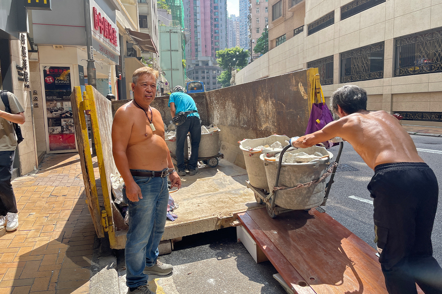 De Hong Kong-aannemer KC Law, links, gefotografeerd op 18 september 2026, zegt dat hij zijn werknemers voorziet van individuele ventilatoren en flessenwater en hen toestaat pauzes te nemen zodat ze de hitte kunnen overleven. Afbeelding met dank aan June Wong voor Mongabay.